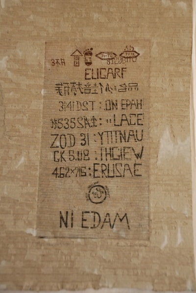Cardboard box with shipping label and postal stamps — print on found material by Elisa Sassera